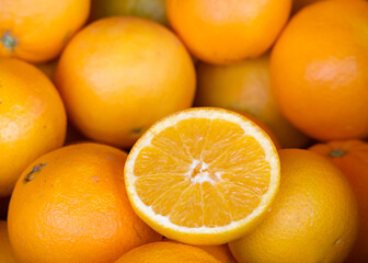 Close up of fresh organic whole navel oranges in a display crate for sale at market. One fruit cut in half for display.