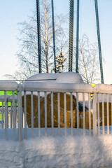 A fragment of a snow-covered empty attraction in a city park on a winter day