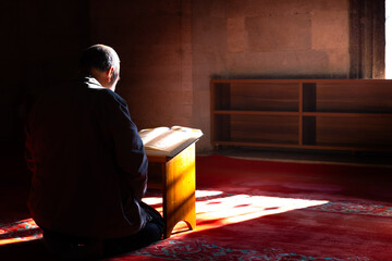 Ramadan or islamic concept. A muslim man reading the Holy Quran in a mosque