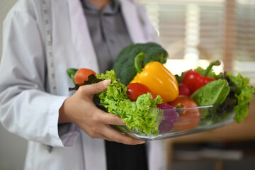 Cropped shot of dietitian holding a bowl of vegetables for healthy eating and diet