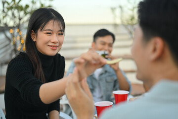 Cheerful young female and male friends enjoying dinner party at rooftop