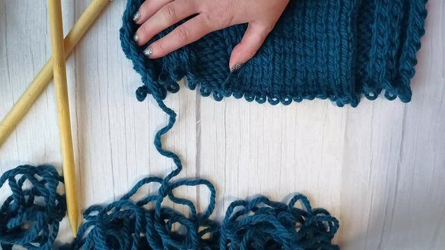 Women's hands tink unravel a knitted product tied with knitting needles. High quality FullHD footage