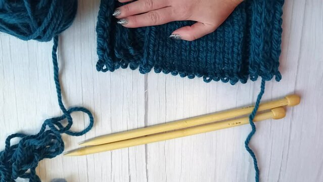 Women's hands tink unravel a knitted product tied with knitting needles. High quality FullHD footage