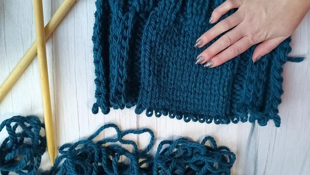 Women's hands tink unravel a knitted product tied with knitting needles. High quality FullHD footage