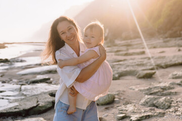 Cheerful mother with her baby on beach with sunshine. Happy family outdoor