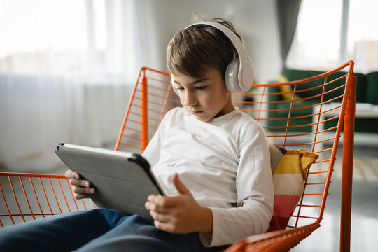 One schoolboy caucasian boy sit at home use digital tablet