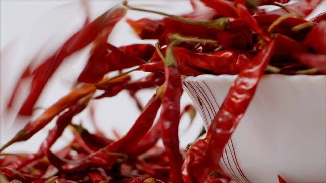 Heap of red peppers overflowing from a white bowl - tropical hot spices  Indian masala  Lal Mirch  traditional seasoning. Closeup shot of dried paprika - Indian gravy and chutney ingredient  Kashmi...