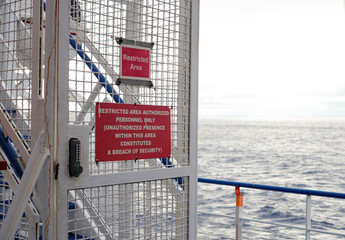 Horizontal Close-Up of Restricted Area Warning Signs on a Ship Metal Gate, Ocean Background, No People, Daytime