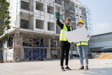 Caucasian engineer man and woman working with paper work at construction site