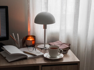 Cozy home desk - Scandinavian style table lamp, candle, work, learning accessories on a wooden table © okkijan2010