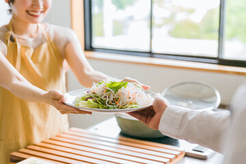 キッチンでサラダを渡す女性夫婦・カップル・男女・主婦・妻
