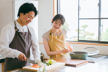 キッチンで料理をする夫婦・包丁で野菜を切る男性
