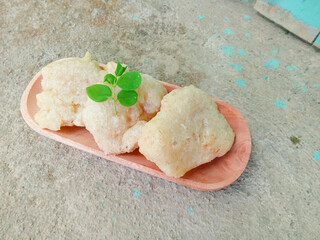 gejos or traditional Indonesian snacks on a wooden plate with a textured background, snacks made from starch mixed with grated coconut and spices then fried. chewy and delicious snack. homemade