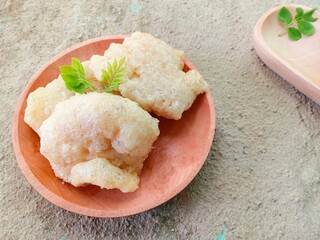 gejos or traditional Indonesian snacks on a wooden plate with a textured background, snacks made from starch mixed with grated coconut and spices then fried. chewy and delicious snack. homemade