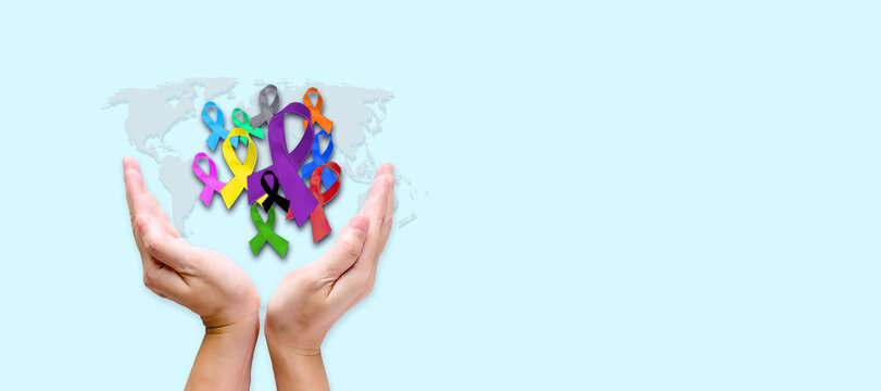 Hand hold many color of ribbons for World cancer awareness day  banner and background. colorful awareness ribbons; blue, red, green, pink and a yellow color