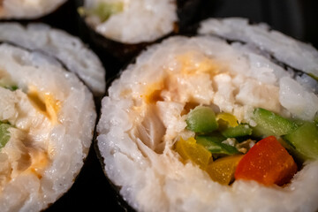 Chop sticks, mushrooms, noodle ramen, California rolls and Philadelphia rolls on a small plate on a pink background
