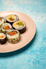 Chop sticks, mushrooms, noodle ramen, California rolls and Philadelphia rolls on a small plate on a blue background
