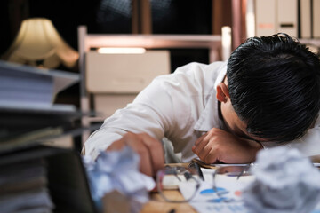 Fototapeta na wymiar Young tired businessman lying on table at night office..
