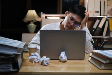 Asian young tired staff businessman using desktop computer having overwork project overnight in...