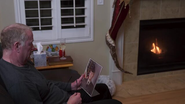 Widower senior man looks at a picture of his son in the army - lost in a foreign war
