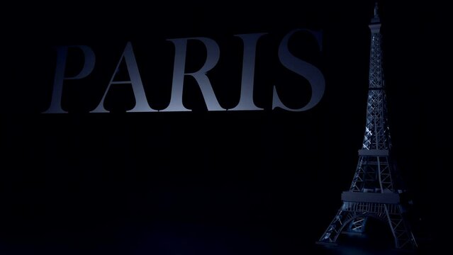 3D animation of Paris lettering and the Eiffel Tower stands tall with word Paris against a black background