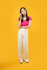 Fototapeta na wymiar Portrait of a young Asian woman having a boring phone call Isolated on a yellow background. 