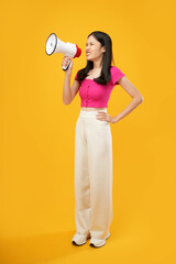 Portrait of a young Asian woman shouting angrily using a megaphone standing and Isolated on a yellow background. 
