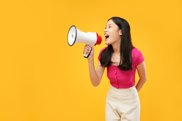 Portrait of a young Asian woman holding a megaphone and shouting aggressively. Wearing a pink...