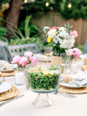 Obraz na płótnie Canvas Beautiful summer tablescape with pink florals and a refreshing salad