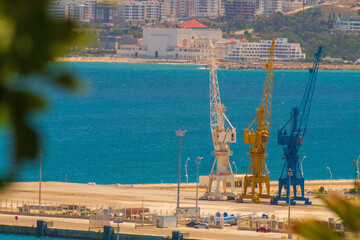 Harbour cranes against the background of the blue sea with slightly blurred contours due to the...