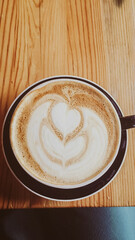 Decorative Cafe Latte in Dark Mug on Wood Table