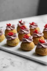 Eclair Choux with pink raspberry cream on a white marble board