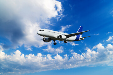 A passenger plane is flying in a beautiful blue sky with white clouds.