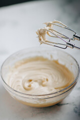 Cream color frosting with a whisk attachments on a white surface