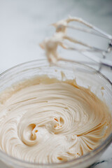 Cream frosting in a bowl with a whisk attachments