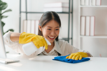 Happy beautiful Asian housewife cleaning various equipment in the office.