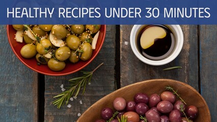 Healthy recipes under 30 minutes text on blue band over bowls of olives and dressing on wood worktop