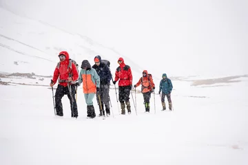 Fotobehang Mount Everest A group of people walking on the snowy mountains with their snowshoes on. Climbing the icy mountains