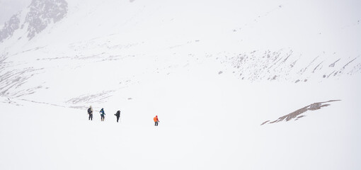 A group of people walking on the snowy mountains with their snowshoes on. Climbing the icy mountains