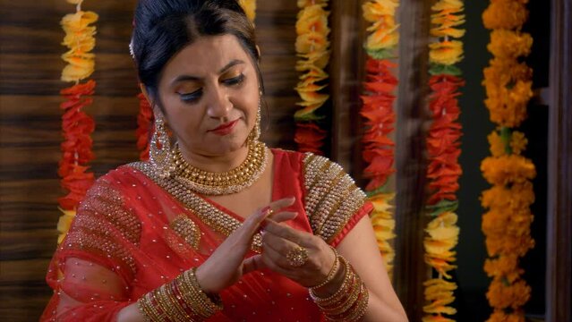 Mid-aged Indian women in traditional red saree getting ready for karva chauth. 