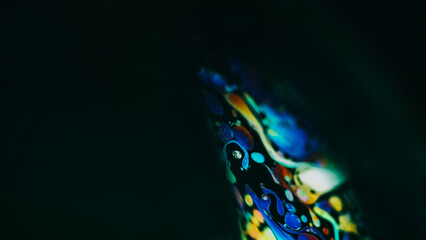 Obraz na płótnie Canvas Ink spill. Paint blend. Blur orange blue red color bubble fluid wave mix motion on dark black abstract art empty space background.