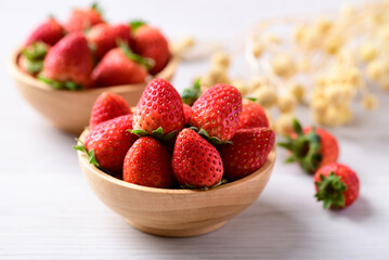 Fresh strawberry fruit in wooden bowl on white background
