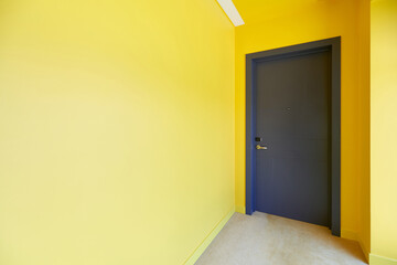 A room with yellow walls and a gray door.