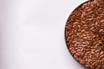 Flax seeds kept on a white background on a wooden spoon