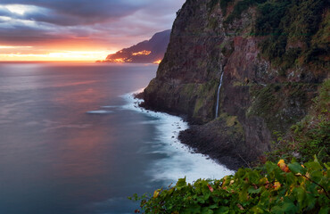 Madeira island - Dramatic sunrise over atlantic ocean with waterfall landscape from Miradouro do...