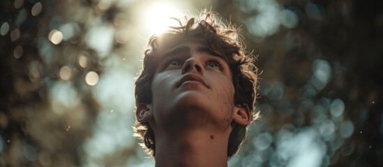 Touched by His Grace. Close-up of a beautiful young man looking up with tears in her eyes. Christian concept - obrazy, fototapety, plakaty