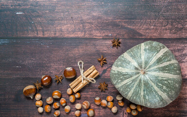 Autumn flatlay with pumpkin, chestnuts, star anise, cinnamon and cobnuts on a brown wooden...