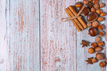 Hestnuts, star anise, cinnamon and cobnuts on a light blue wooden background with copyspace