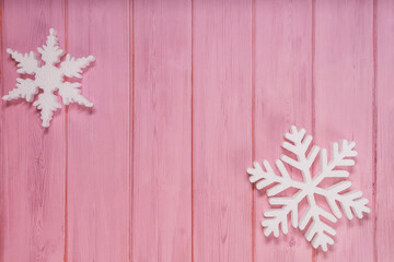 Two white snowflakes on a pink wooden background topview. New Years flatlay with copyspace