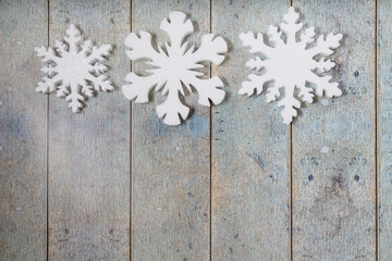 Three snowflakes on a light blue wooden background. Christmas winter flatlay with copyspace
